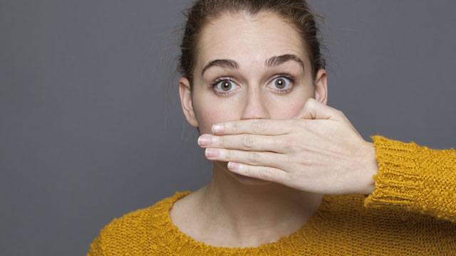 portrait of surprised beautiful 20s girl covering her mouth for bad breath