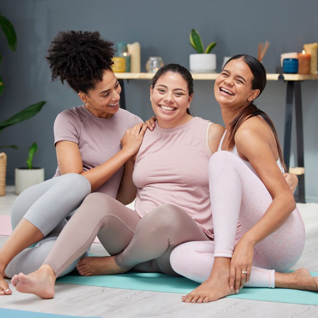 women in yoga class hugging or bonding with a happy smile