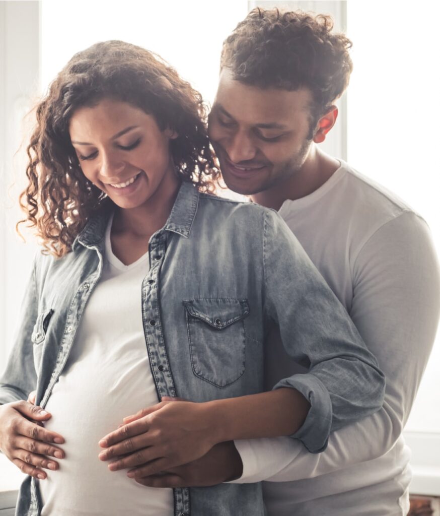 Handsome man and his beautiful pregnant wife are hugging