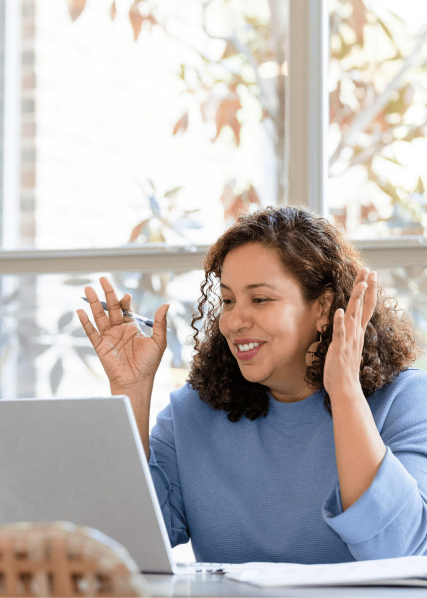 Woman talking during online therapy in Virginia on a laptop in front of a window.