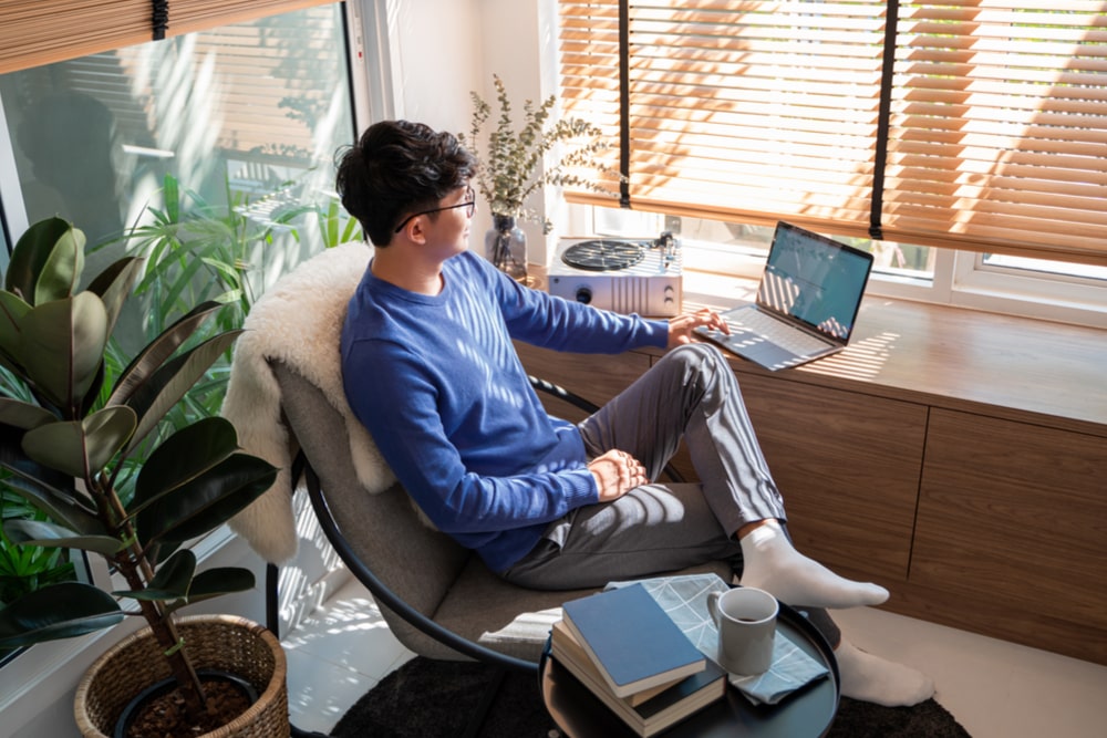 male tech user relaxing holding laptop