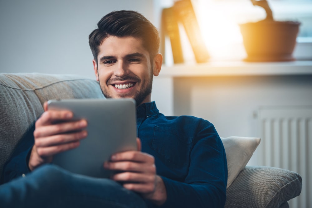 Handsome young man using his digital tablet with smile