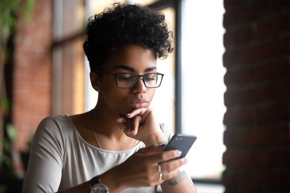 woman wearing glasses holding phone browse internet