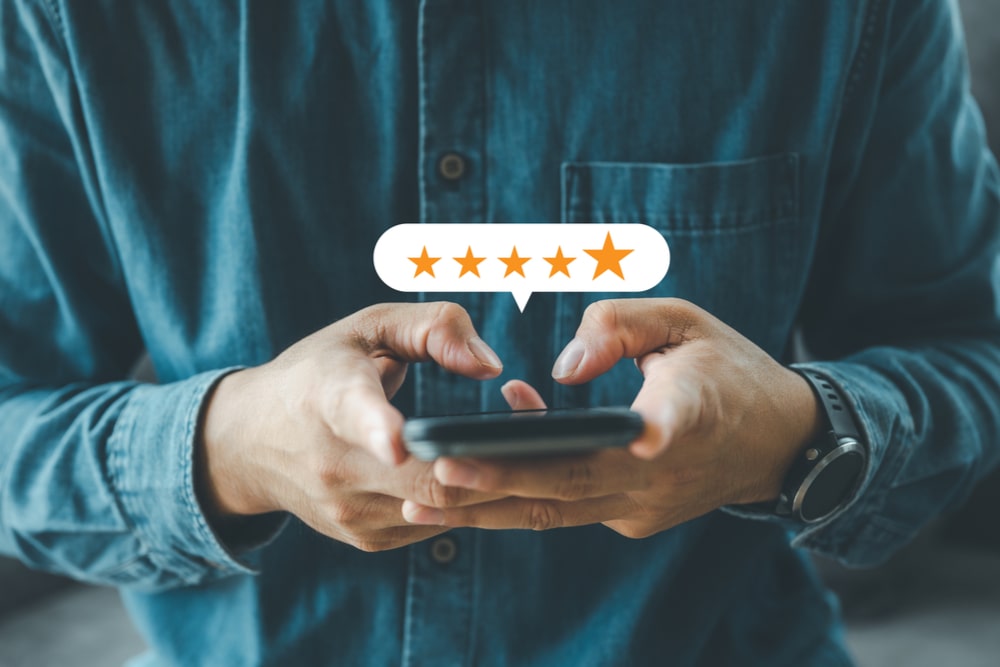 Man hand using smartphone with popup five star icon for feedback review