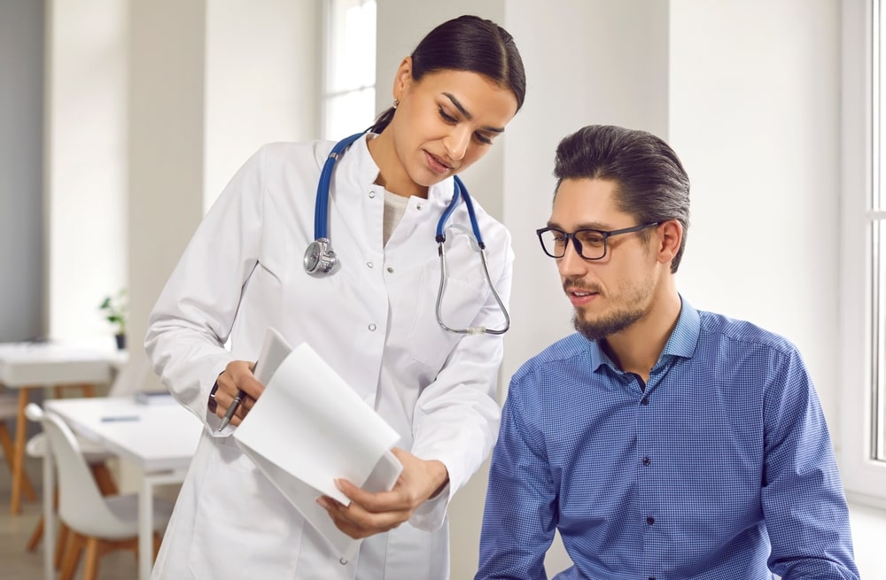 Female doctor showing test results to male patient in medical clinic.