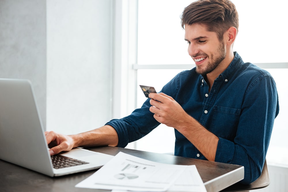 man holding a credit card and typing. Online