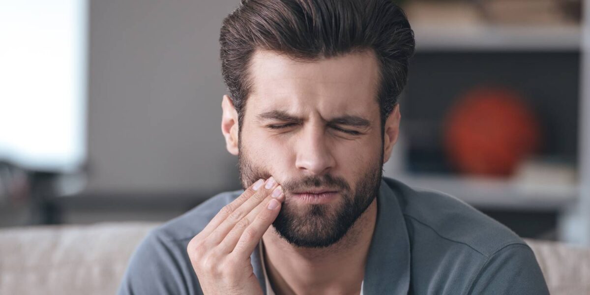 Frustrated young man touching his cheek