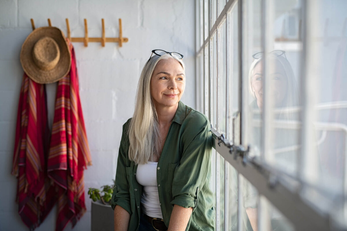 Smiling mature woman looking outside window.