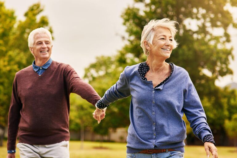 Aged couple smiling and holding hands