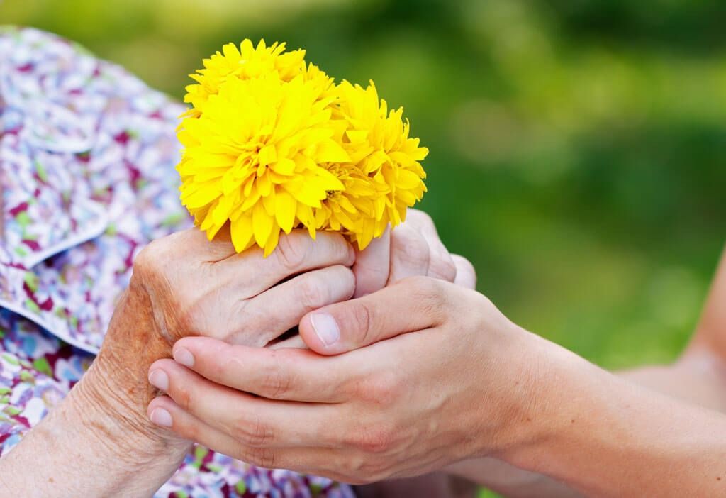 Man giving a yellow flower to senior woman