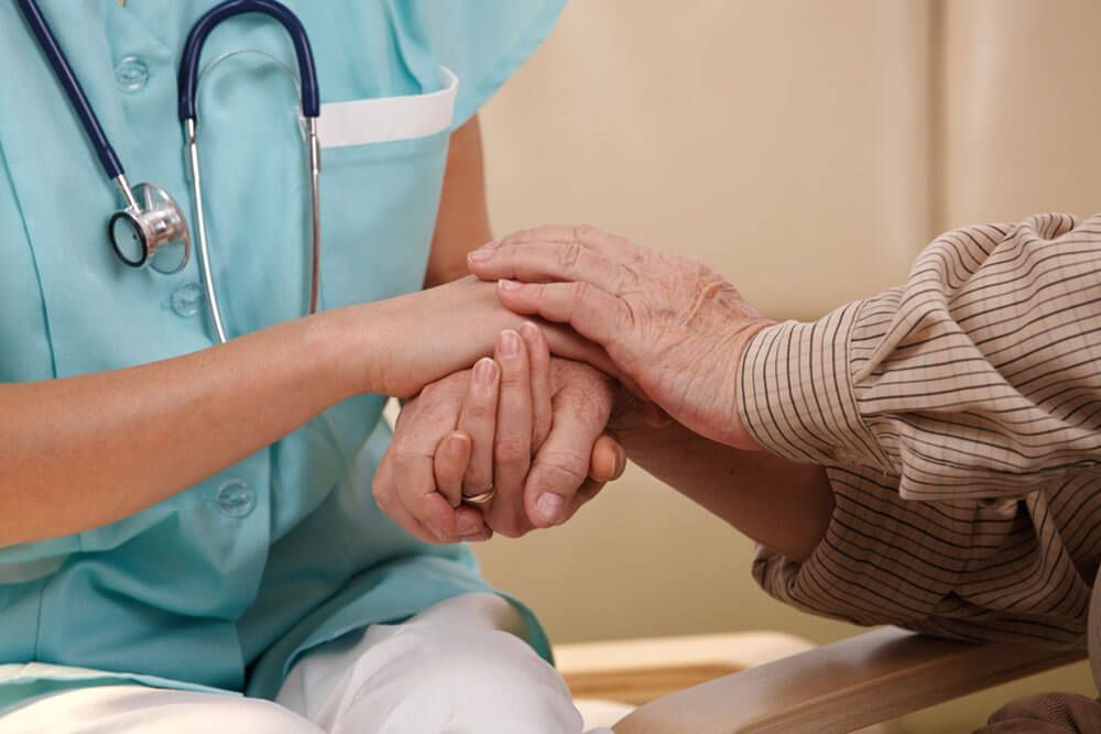 Closeup of joined hands of nurse and elderly patient