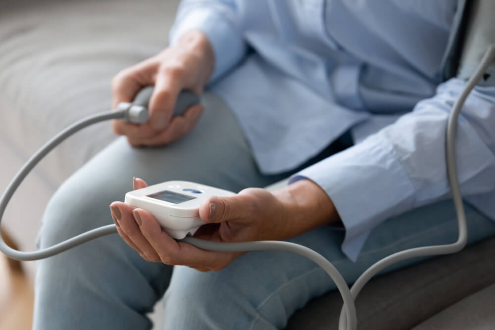 woman checking blood pressure with digital tonometer at home