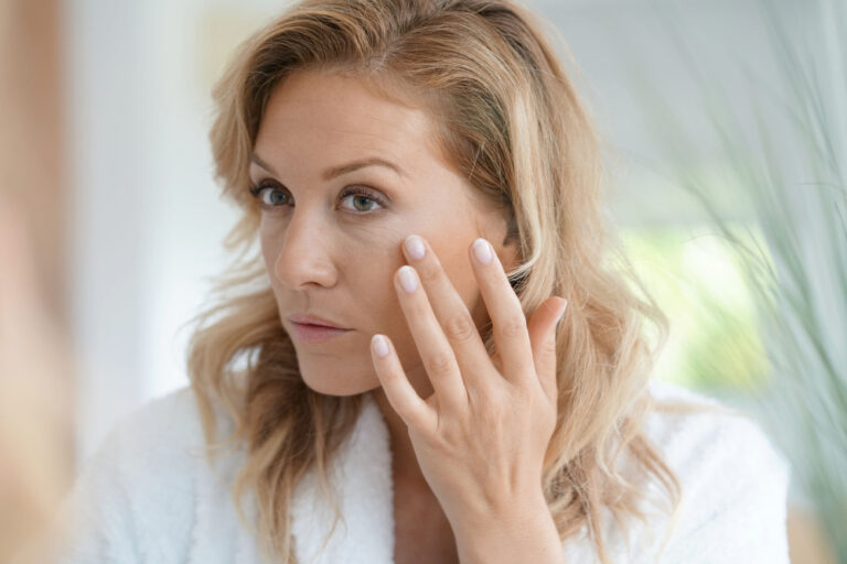 Attractive woman applying cream on face