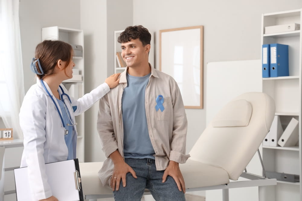 Young man with blue ribbon and female doctor in clinic. Prostate cancer awareness concept