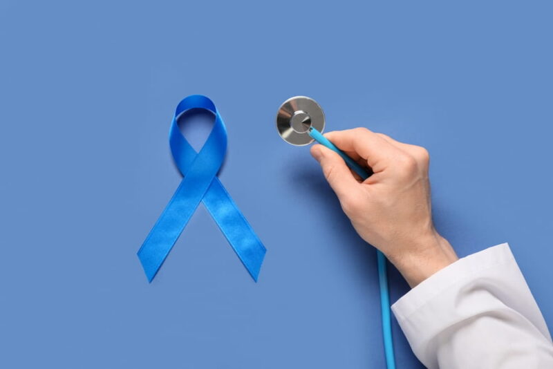 Male doctor's hand with blue ribbon and stethoscope