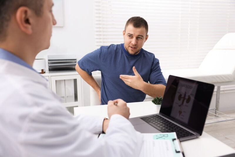 Man having appointment with urologist at white desk in clinic
