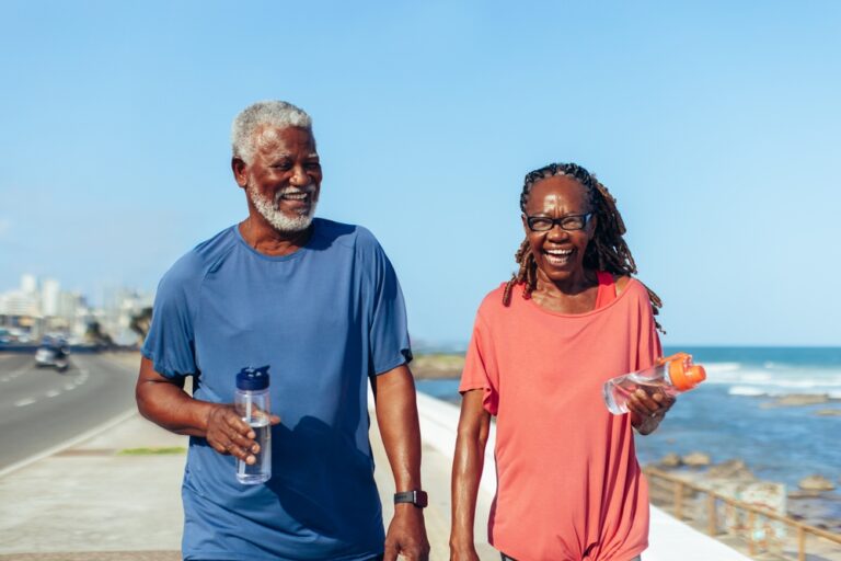 Promenade walk: An older black couple happily walking together along a seaside promenade