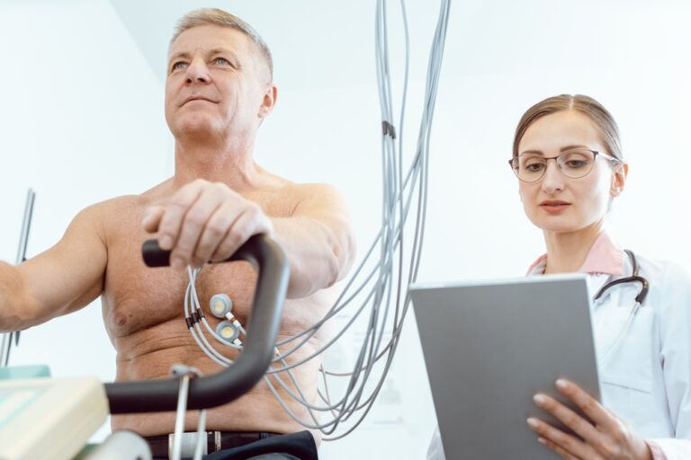 Doctor taking notes on tablet computer during stress ECG
