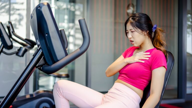 Tired asian woman having heart attack after doing sport hand holding her chest pain