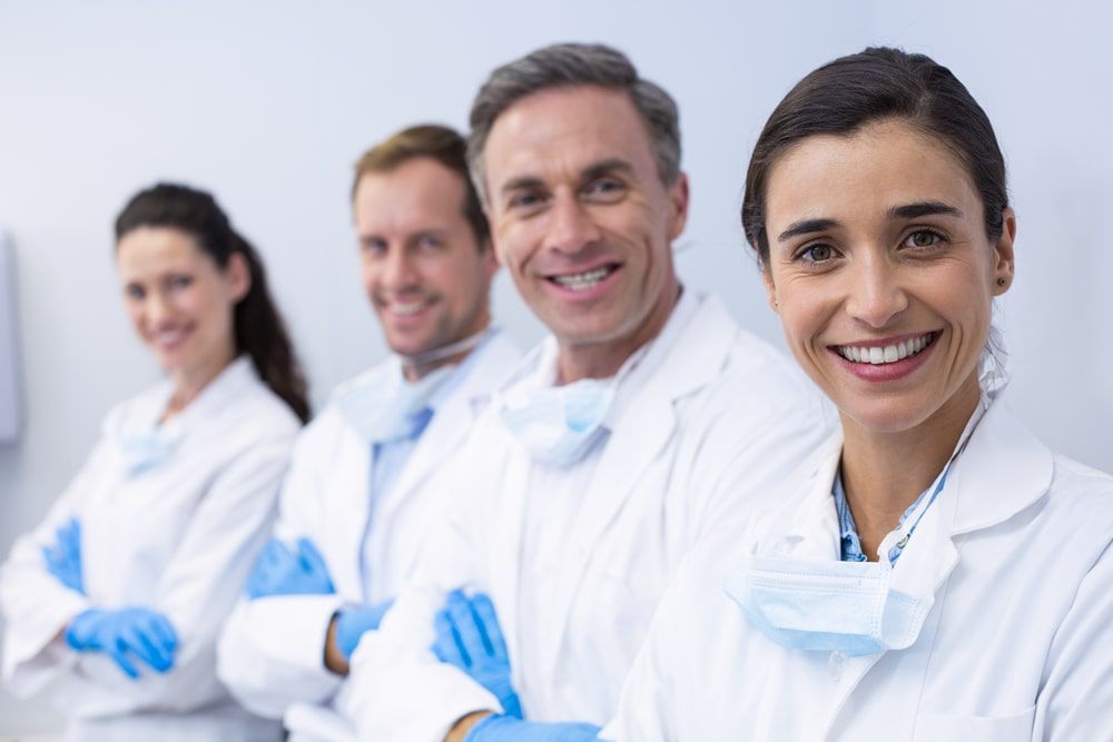 smiling dentists standing with arms crossed in dental clinic
