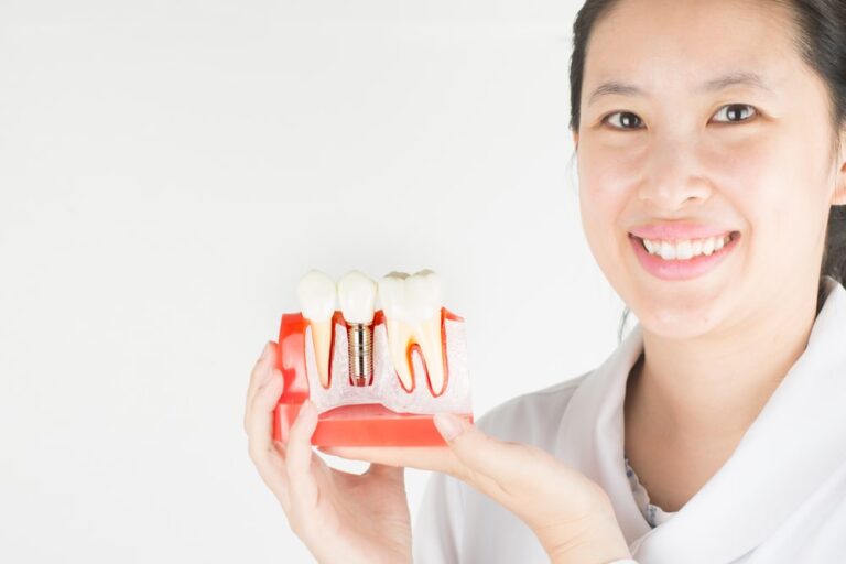 Dentist show model of dental implant inside gums.