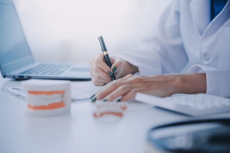 Dentists are discussing dental problems at report x-ray image on laptop screen to patients.