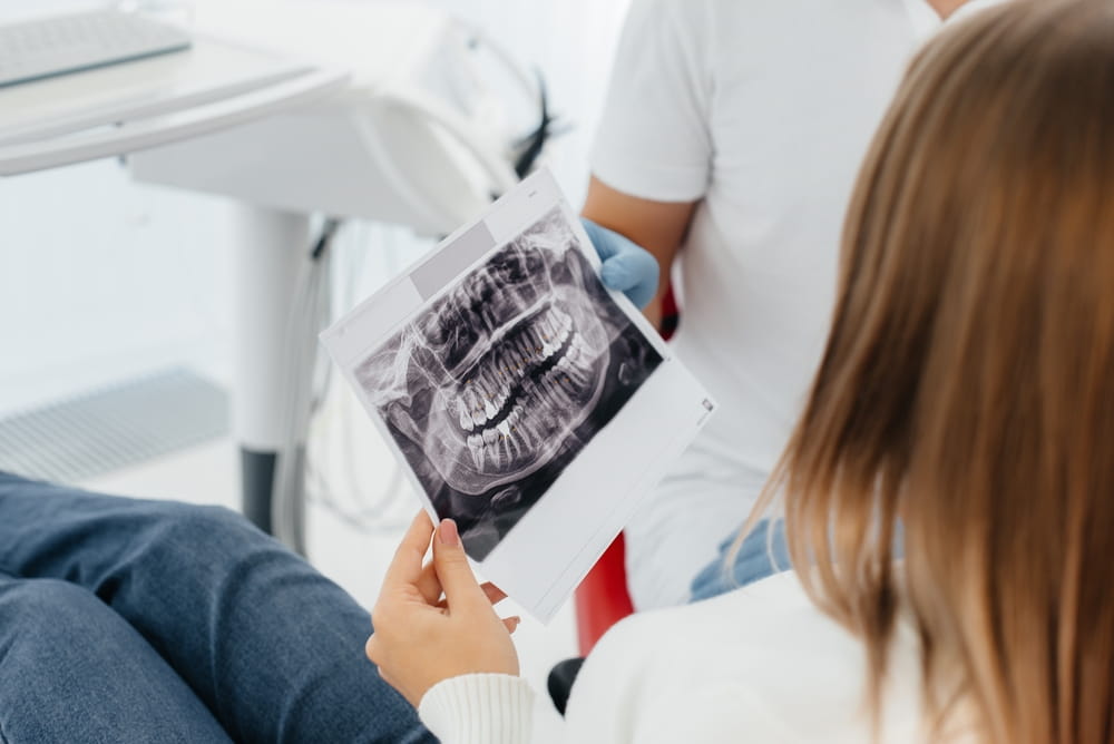The dentist advises a young beautiful woman about the treatment and prosthetics of teeth in modern white stomatolgia. Dental prosthetics, treatment and teeth whitening.