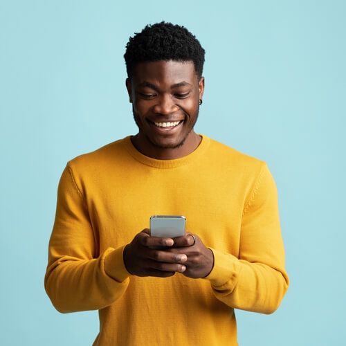 Joyful african american millennial guy holding modern smartphone