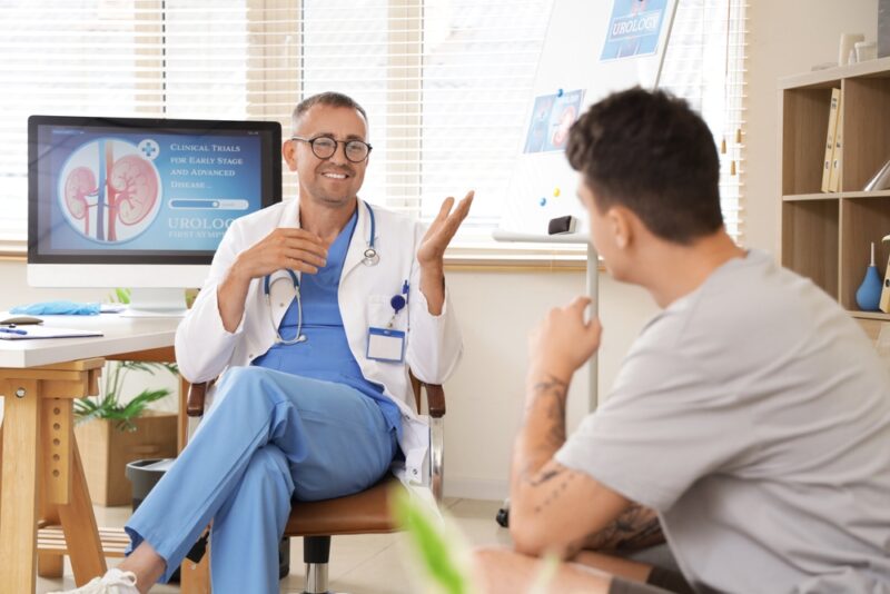 Mature urologist talking to young man in clinic