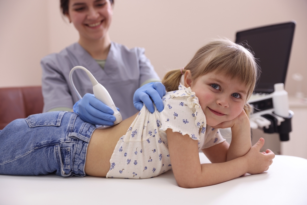 Sonographer conducting little girl's renal ultrasound examination in clinic, closeup