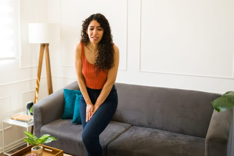 Anxious hispanic young woman wanting to go to the bathroom and suffering from urinary incontinence