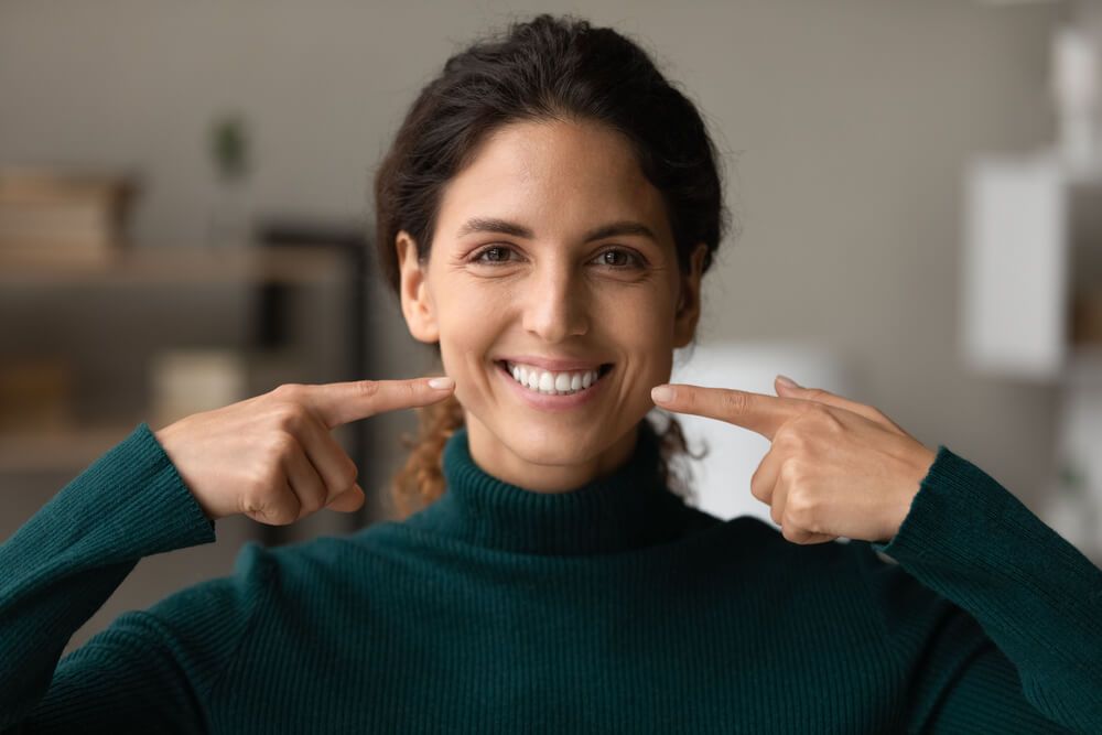 happy woman pointing fingers at healthy toothy smile