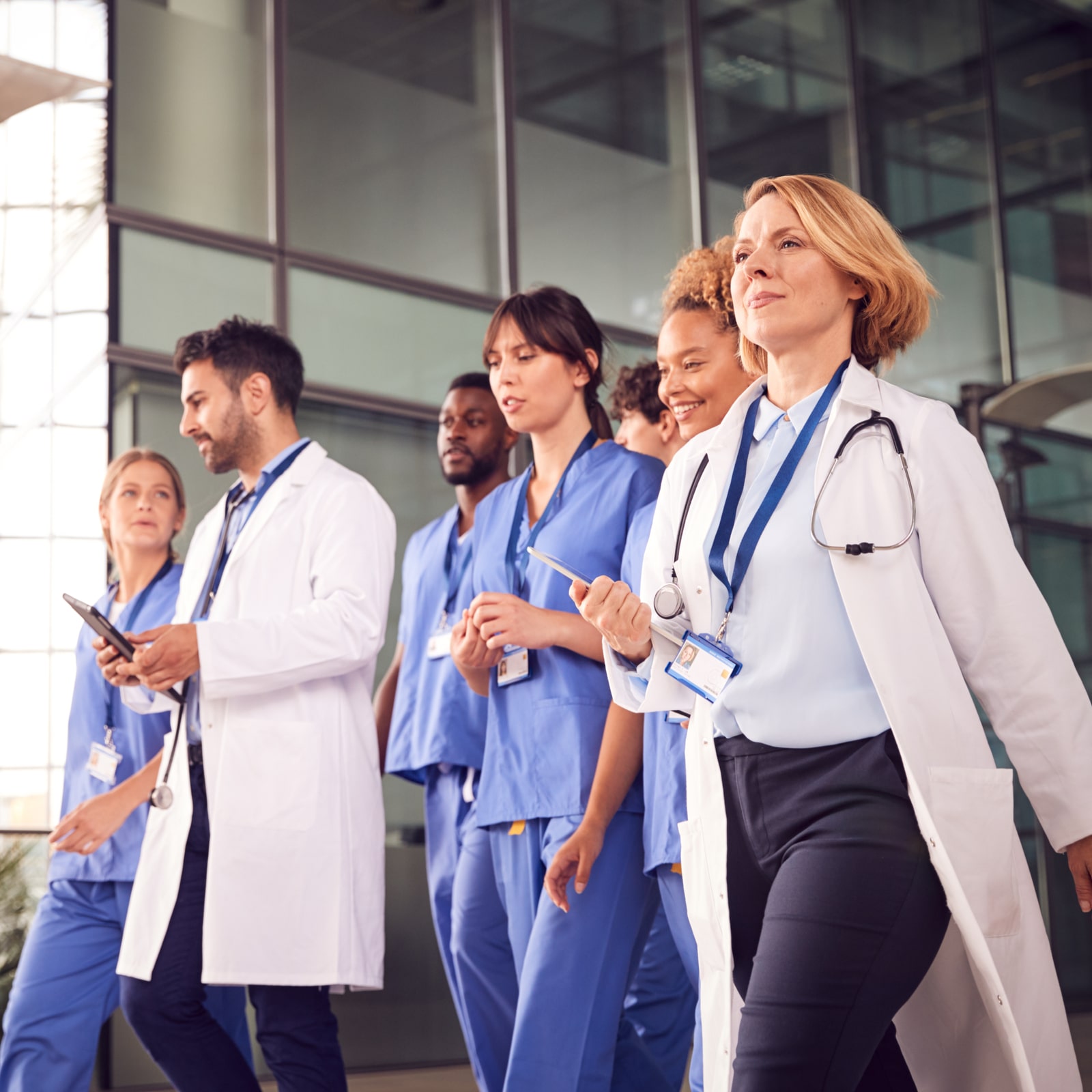 Medical Team Walking Through Lobby Of Modern Hospital Building