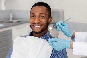 Dentist tools in doctor hands and cheerful african guy in dentist chair