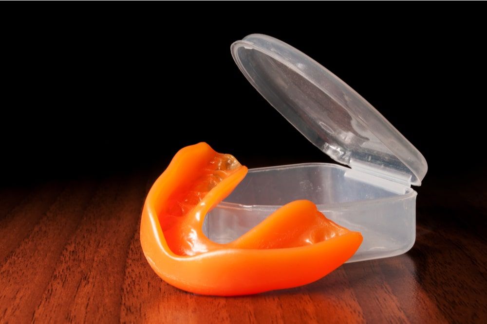 Orange mouthguard near opened case on the wooden texture