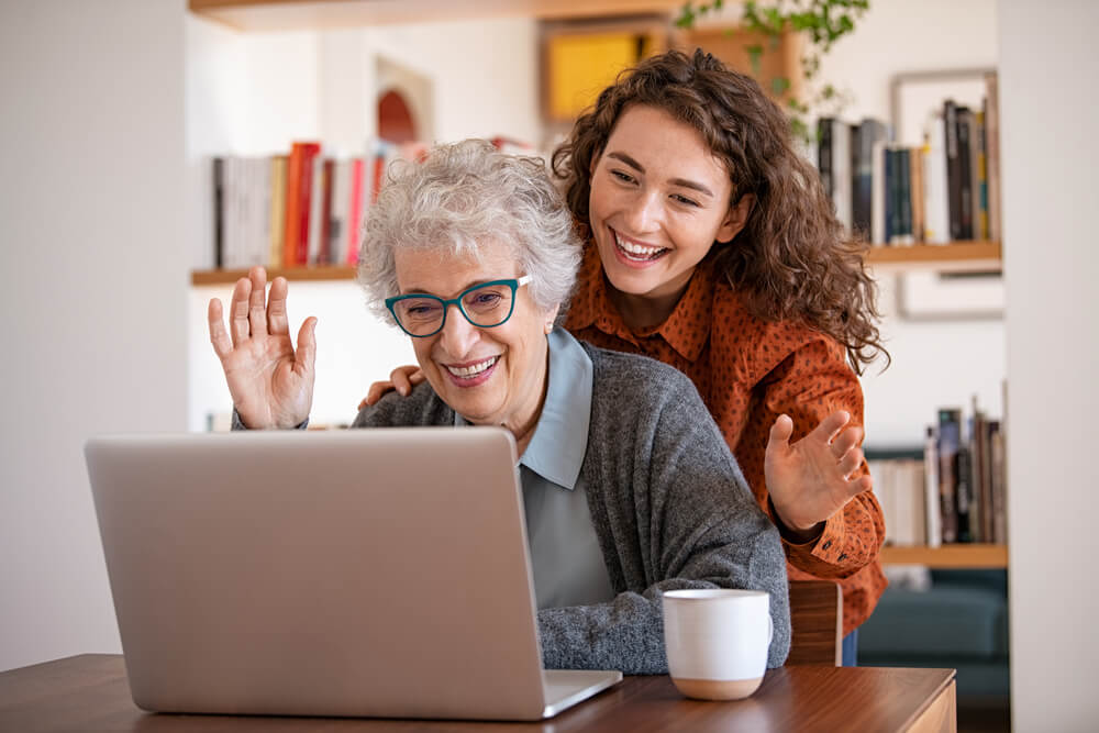 Granddaughter with grandmother waving hand during video call