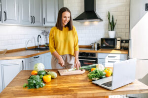 Cheerful young woman cooking with a movie