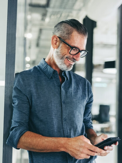 Cheerful businessman sending a text message in an office