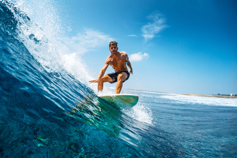 Young athletic surfer rides the wave in tropics with splashes