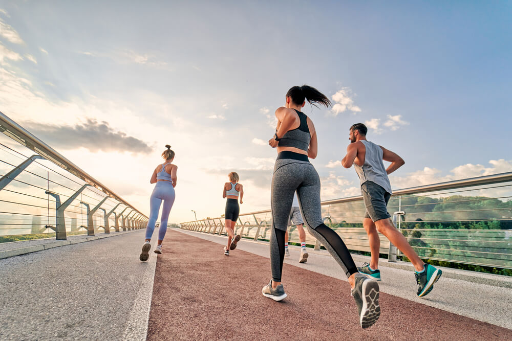 Group of sporty young people running outdoors. Doing sport on the sttreet