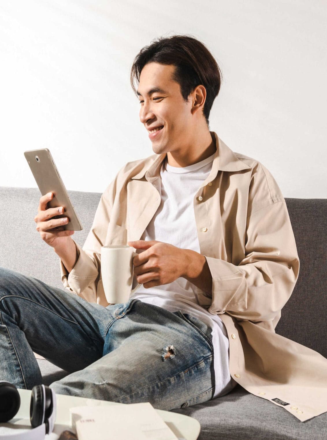 Happy smiling Asian student sits and relaxes on a couch