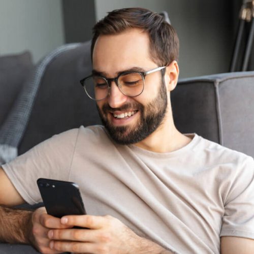 Attractive smart young man sitting on a floor in the living room