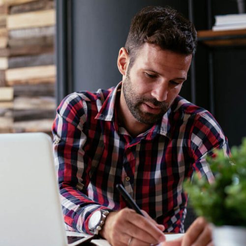 Businessman taking a notes while working on laptop