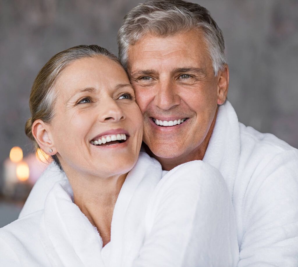 Smiling husband embracing cheerful wife from behind at spa