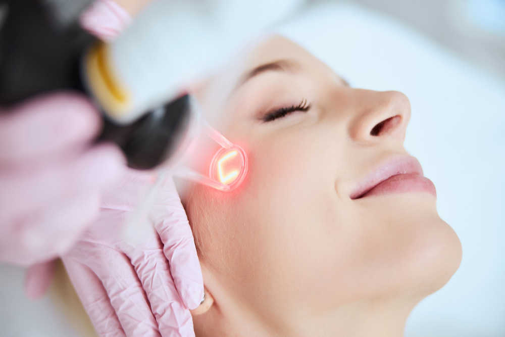 Close up portrait of a young woman patient receiving a laser treatment in a spa salon