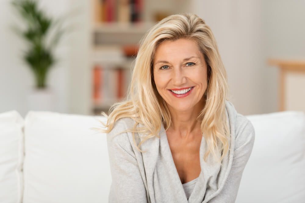 middle-aged blond woman with a beaming smile sitting
