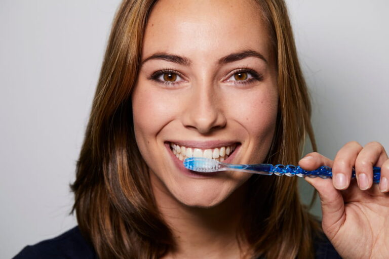 Brown eyed girl brushing teeth to camera, studio
