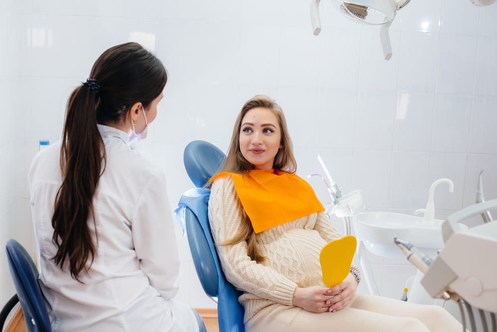 A professional dentist treats and examines the oral cavity of a pregnant girl in a modern dental office. Dentistry