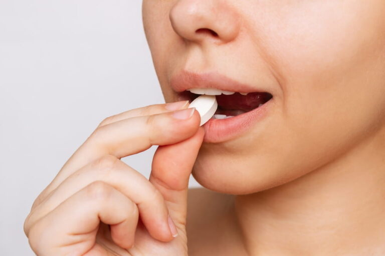 Cropped shot of a young caucasian woman taking a pill