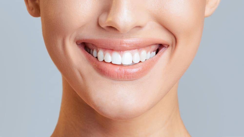 Woman mouth smiling. Her teeth are white and healthy, and she has a gentle smile on her face